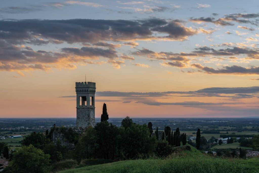 Paesaggio al tramonto con torre circondata da alberi