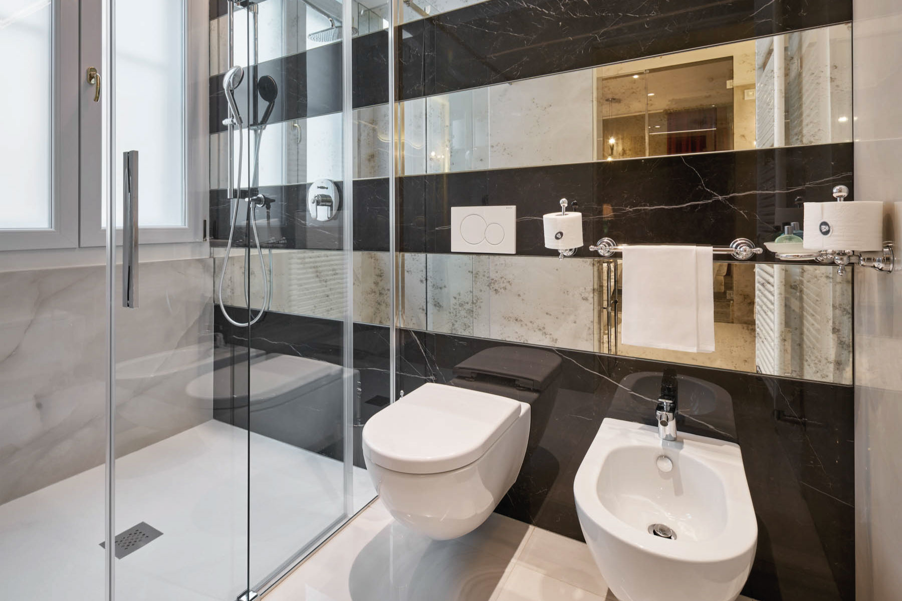 Bagno elegante con wc e bidet affiancati. Parete di design